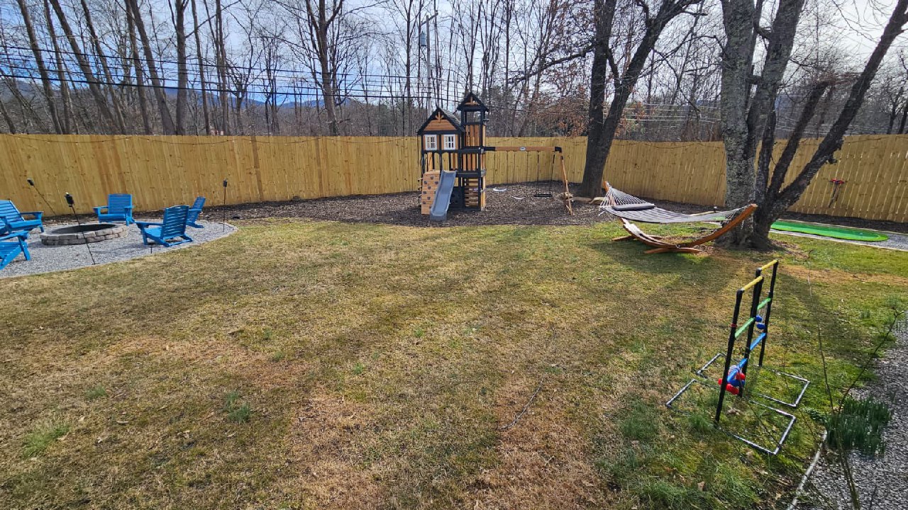 Backyard with hammock, kids playset, fire pit, and ladder golf
